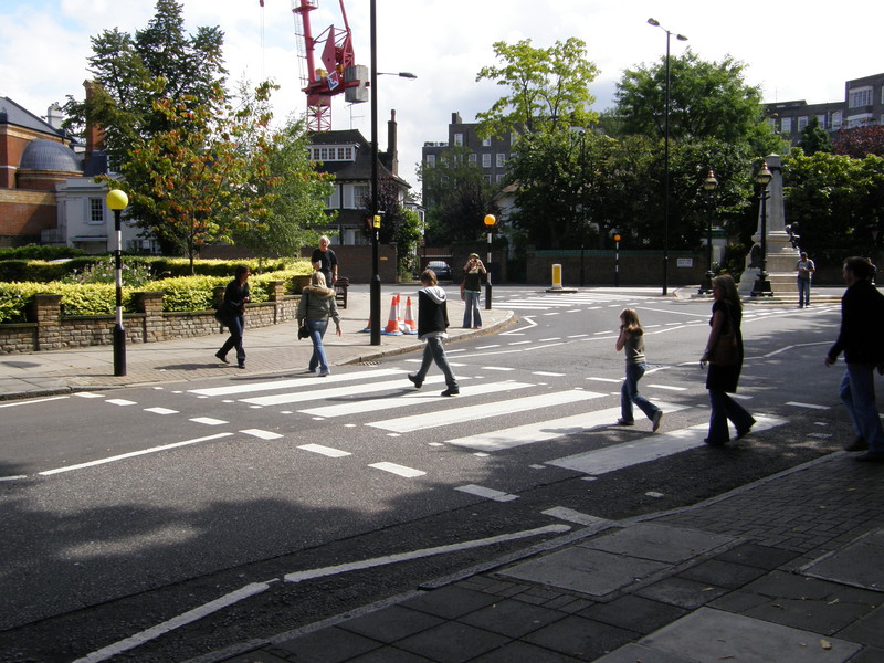 Tourists walking across the famous Abbey Road zebra crossing